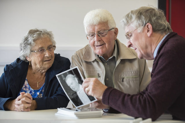 Three older people looking at an old photograph