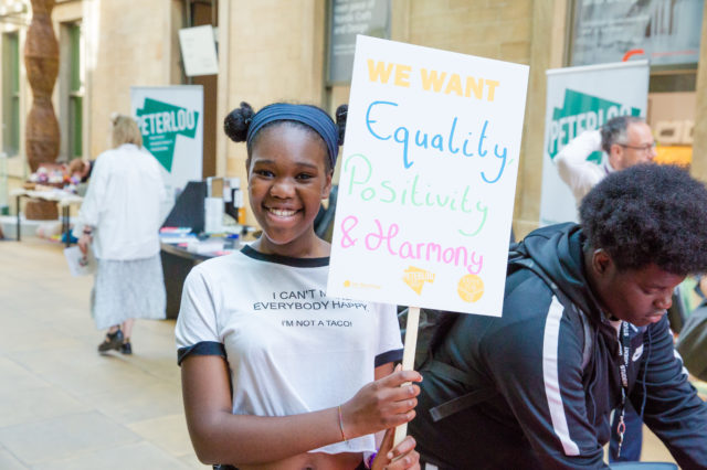Young Woman holding banner saying Equality Diversity Harmony