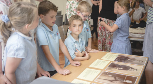 children standing at a table looking at old photographs
