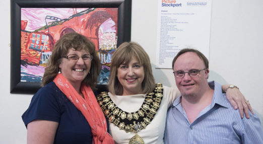 Group picture of three people in front of art work in Stockport Art Gallery