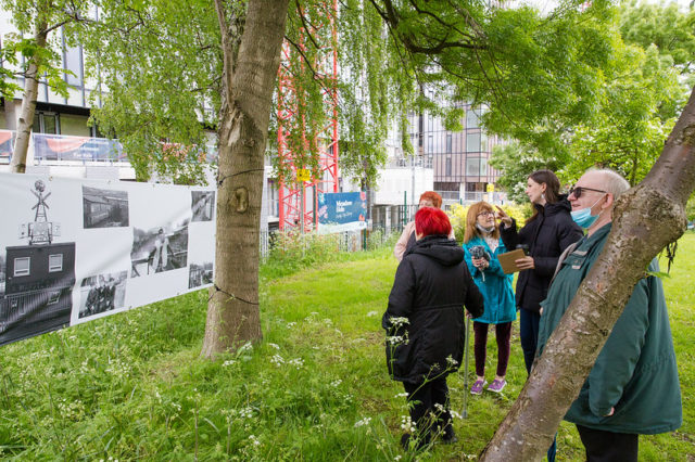 People standing in Angel Meadow park looking at an photography exhibition set between trees