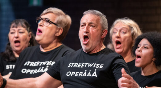 Five people singing wearing t-shirts saying 'Streetwise Opera'