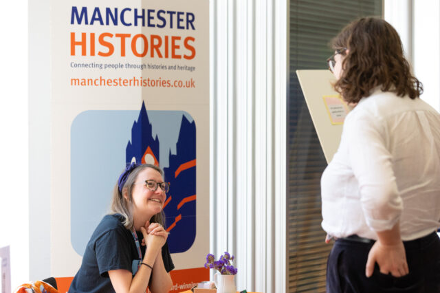 Manchester Histories General Manager Abbie talking with visitor to Manchester Histories stall.