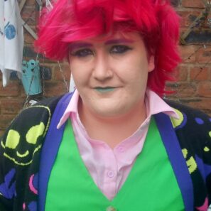 Image of Quen - person with pink hair wearing a bright green waistcoat.