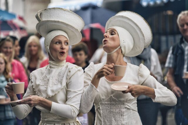 Two women with tea cups on their heads