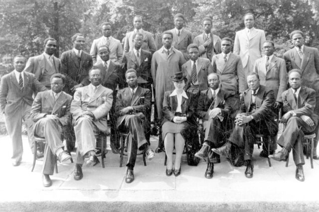 A group of black men and one white woman sitting on chairs as part of the Pan African Congress in Manchester