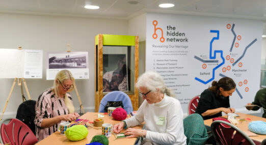 A group of people sat around a table weaving in Manchester Histories Hub