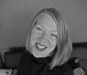 Black-and-white portrait of Alyson Campbell smiling at the camera, with straight shoulder-length hair.