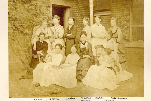 Sepia group photograph of twelve women students posed outside Benslow House in Hitchin in 1871–72, including Rachel Cook, later Rachel Scott.