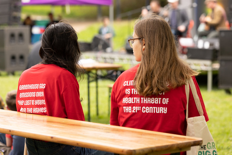 Two people wearing red climate awareness T-shirts at an outdoor event during the Manchester Histories Festival 2022.